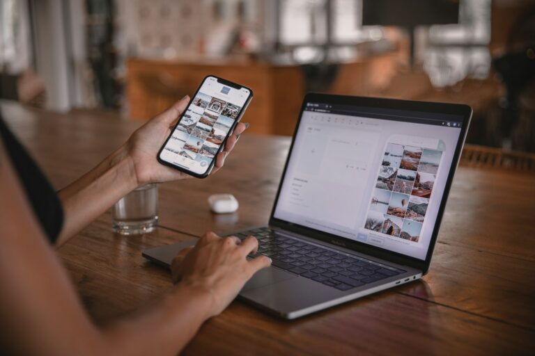 Woman reviewing an online website on a laptop while holding a smartphone